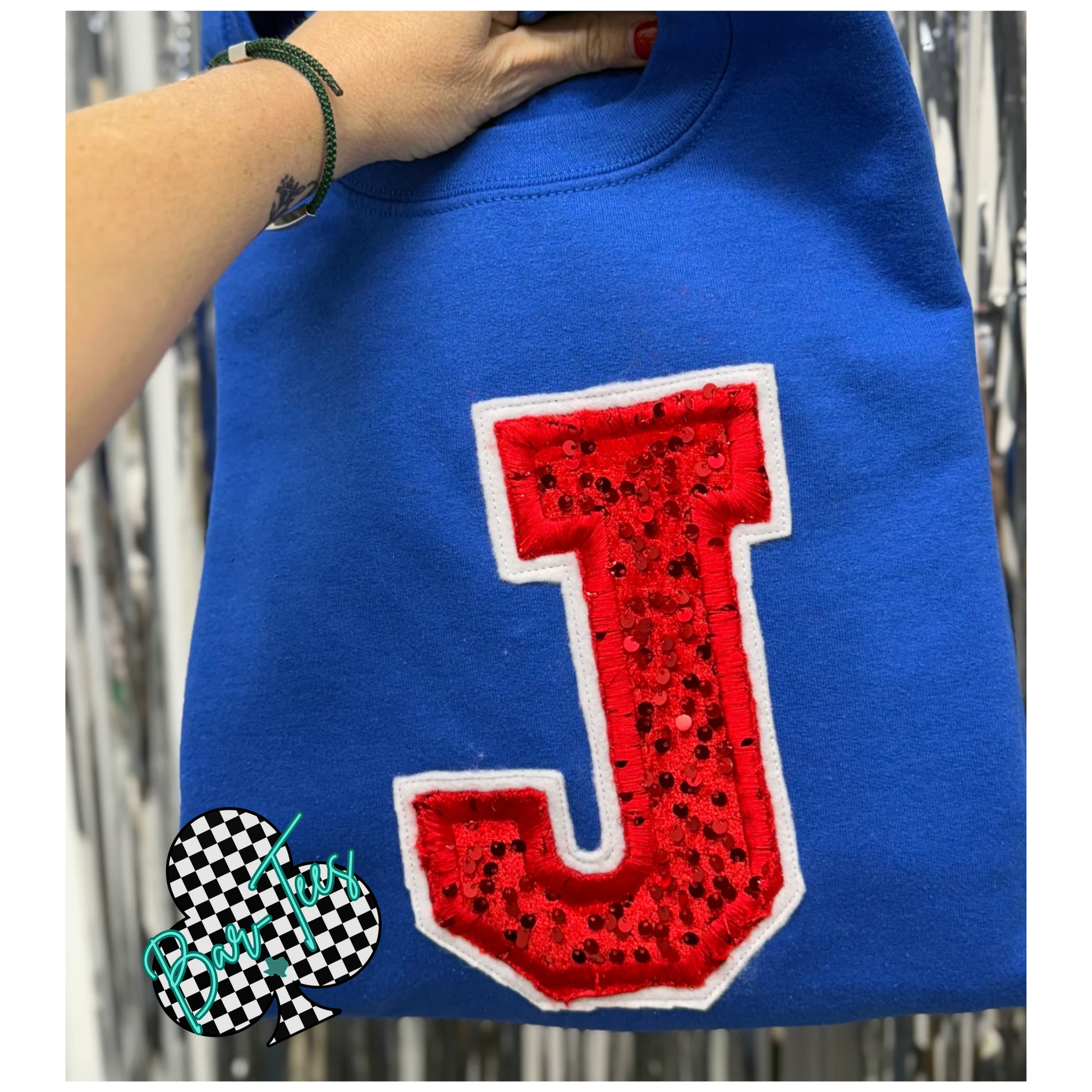 Blue shirt with a red 'J' patch worn by a person, with a blurred background.